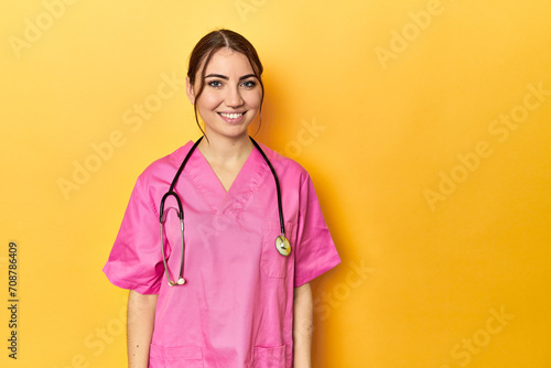 Nursing assistant in yellow background happy, smiling and cheerful. © Asier