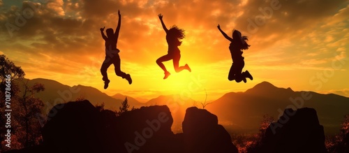 Silhouette three people jumping on mountain sunset sky background. Friends jumping on the beach under sunset sunlight.