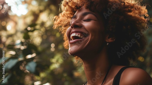 Joyful woman with curly hair laughing in natural light