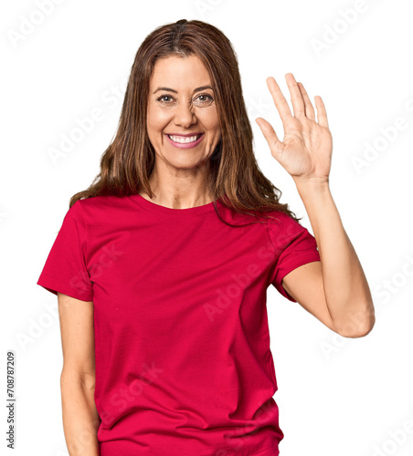 Middle-aged woman portrait in studio setting smiling cheerful showing number five with fingers.