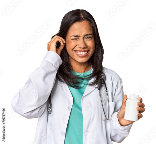 Young Filipina doctor holding a pill bottle covering ears with hands.