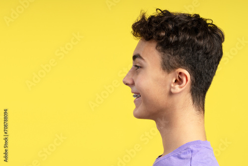 Side view portrait of handsome smiling young boy with dental braces looking away copy space photo