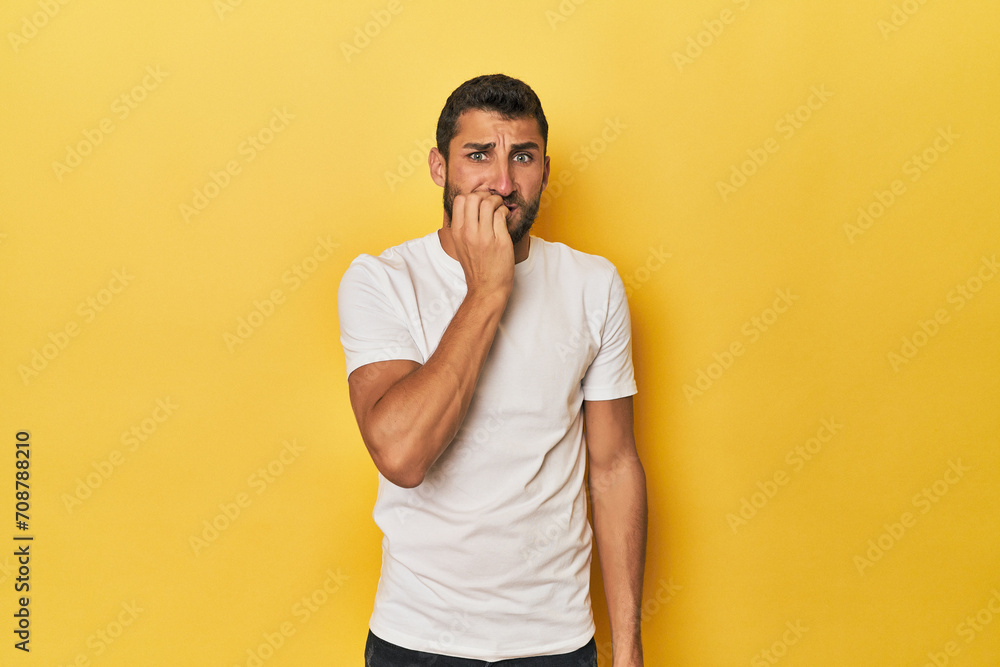 Young Hispanic man on yellow background biting fingernails, nervous and very anxious. Young Hispanic man on yellow background biting fingernails, nervous and very anxious.