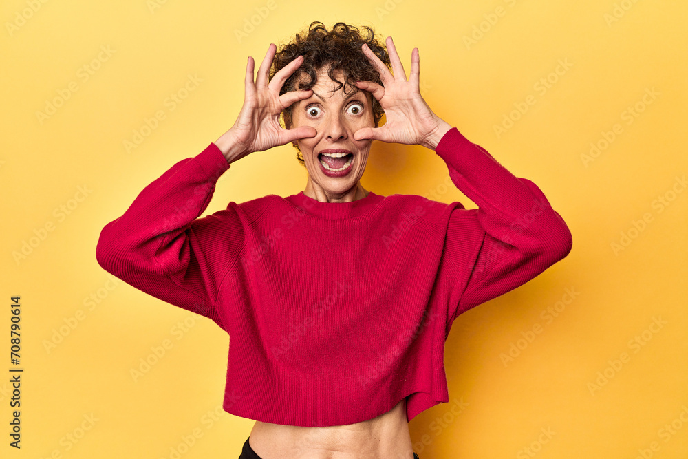 Mid-aged caucasian woman on vibrant yellow keeping eyes opened to find a success opportunity. Mid-aged caucasian woman on vibrant yellow keeping eyes opened to find a success opportunity.