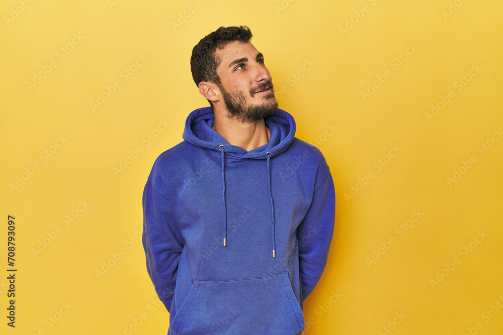 Young Hispanic man on yellow background relaxed and happy laughing, neck stretched showing teeth. Young Hispanic man on yellow background relaxed and happy laughing, neck stretched showing teeth.