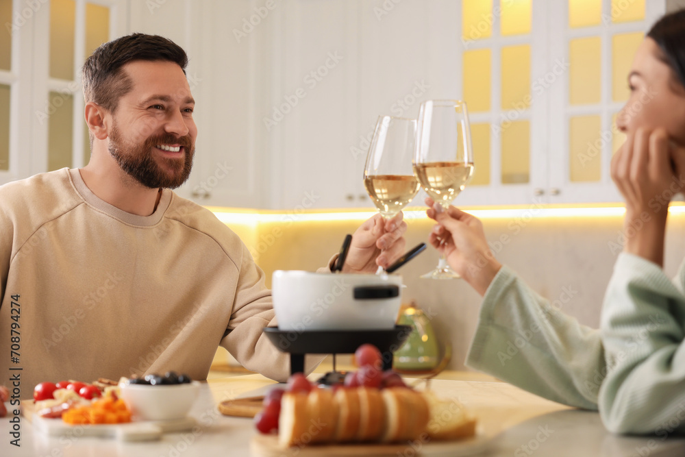 Romantic date with fondue. Couple clinking glasses of wine at home Romantic date with fondue. Couple clinking glasses of wine at home