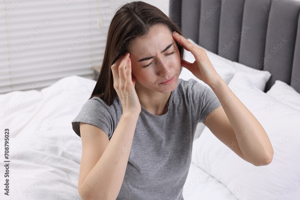 Sad woman suffering from headache on bed indoors Sad woman suffering from headache on bed indoors