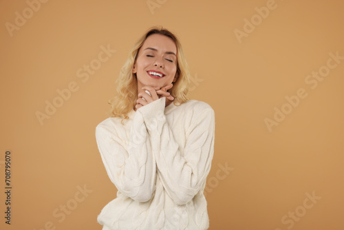 Happy woman in stylish warm sweater on beige background