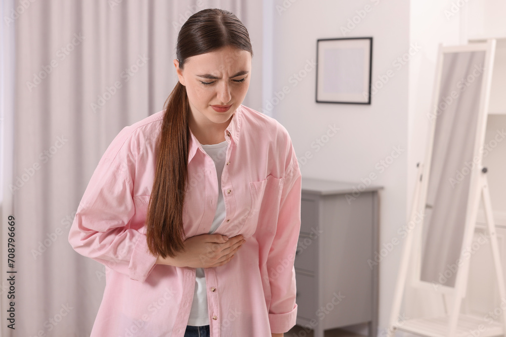 Young woman suffering from stomach pain at home. Space for text Young woman suffering from stomach pain at home. Space for text
