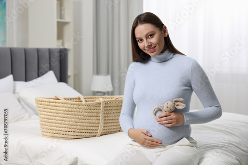 Beautiful pregnant woman with bunny toy in bedroom