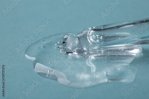 Pipette with cosmetic serum on light blue background, closeup. Space for text