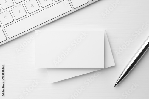 Blank business cards  keyboard and pen on white table  flat lay. Mockup for design