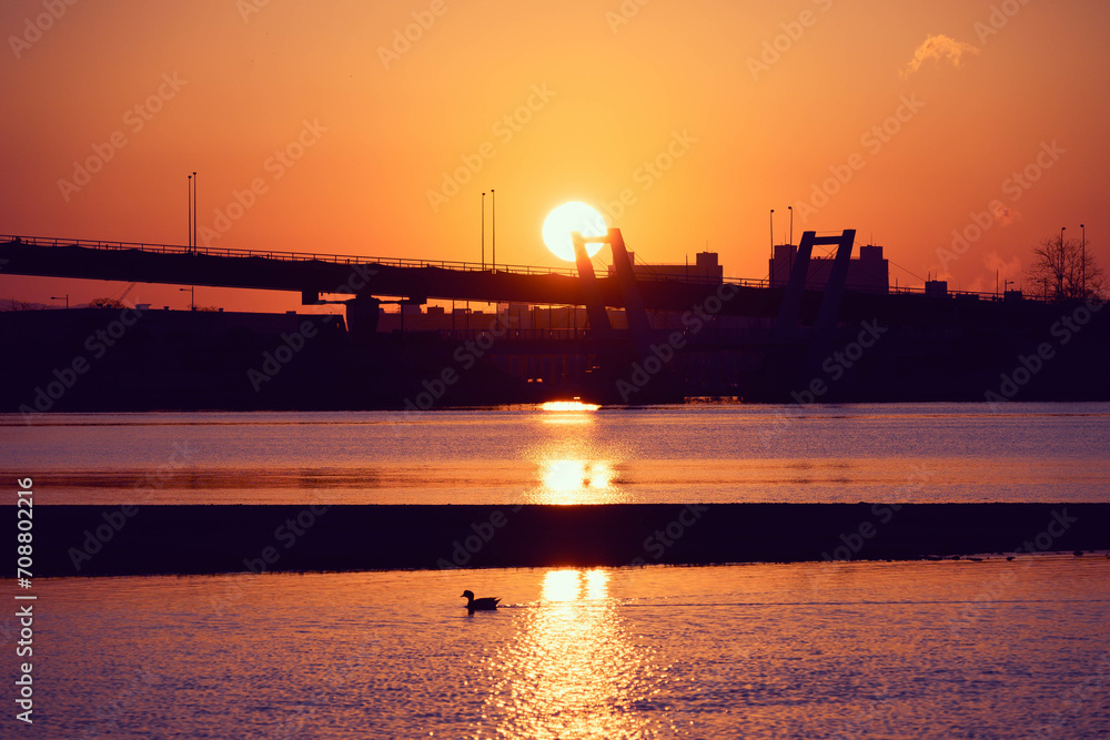 都市の夜明け。橋の上から太陽の日が登る。兵庫県西宮市の香櫨園浜で撮影