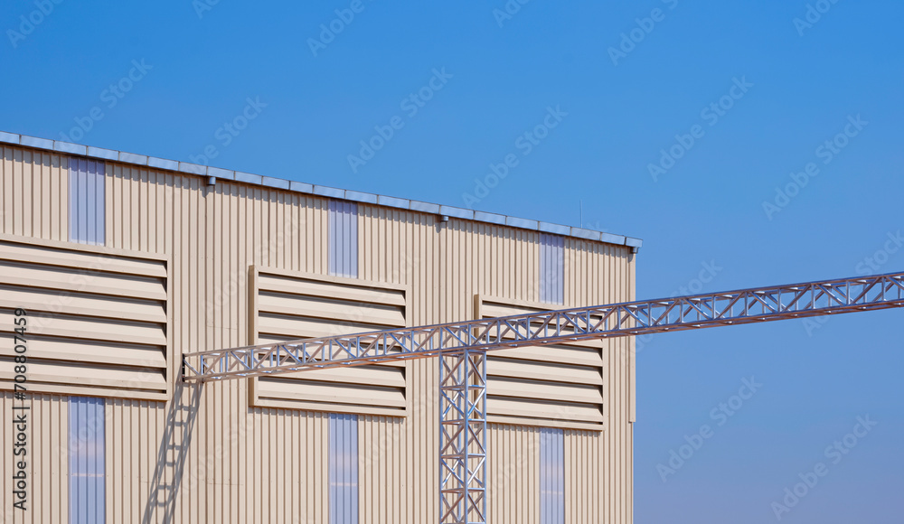 Three aluminium louvers on corrugated metal wall with rain gutter and overhead electrical cable ladder of modern industrial factory building against blue clear sky background Three aluminium louvers on corrugated metal wall with rain gutter and overhead electrical cable ladder of modern industrial factory building against blue clear sky background