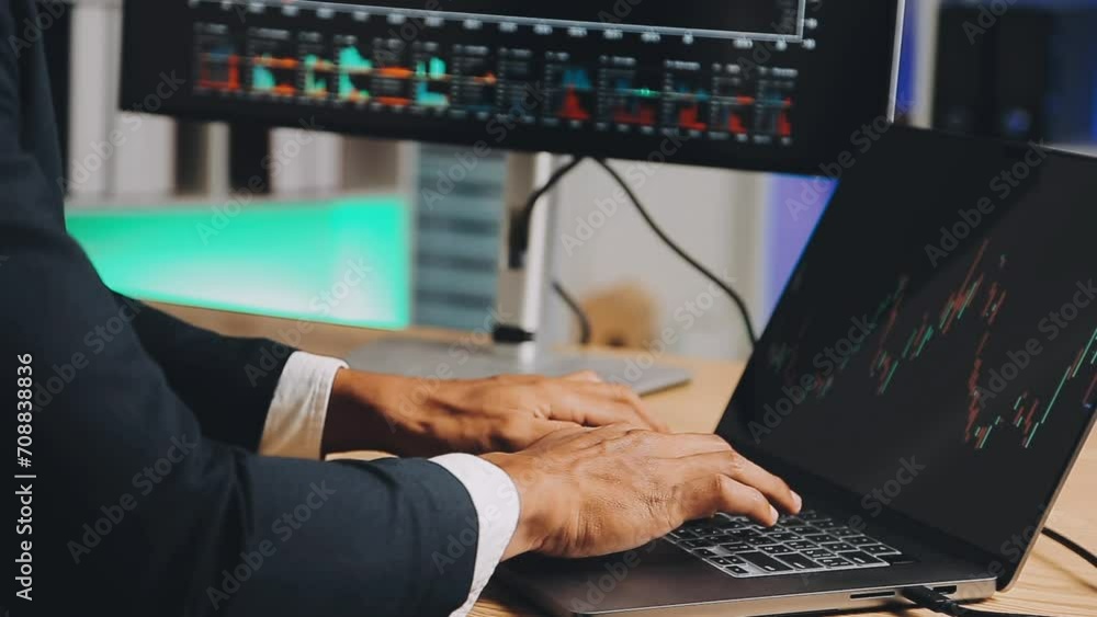 Financial Analyst Working on a Computer with Multi-Monitor Workstation with Real-Time Stocks, Commodities and Foreign Exchange Charts. Businessman Works in Investment Bank City Office at Night. Financial Analyst Working on a Computer with Multi-Monitor Workstation with Real-Time Stocks, Commodities and Foreign Exchange Charts. Businessman Works in Investment Bank City Office at Night.