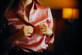 Hands of a Woman Unbuttoning her Shirt at Home. Seductive girl wearing a silk blouse undressing in low light bedroom 
