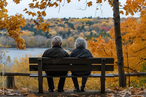 Elderly couple sitting on a bench. Autumn background