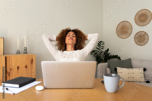 Front view of young multiracial hispanic female entrepreneur relaxing at home office taking a break feeling satisfaction