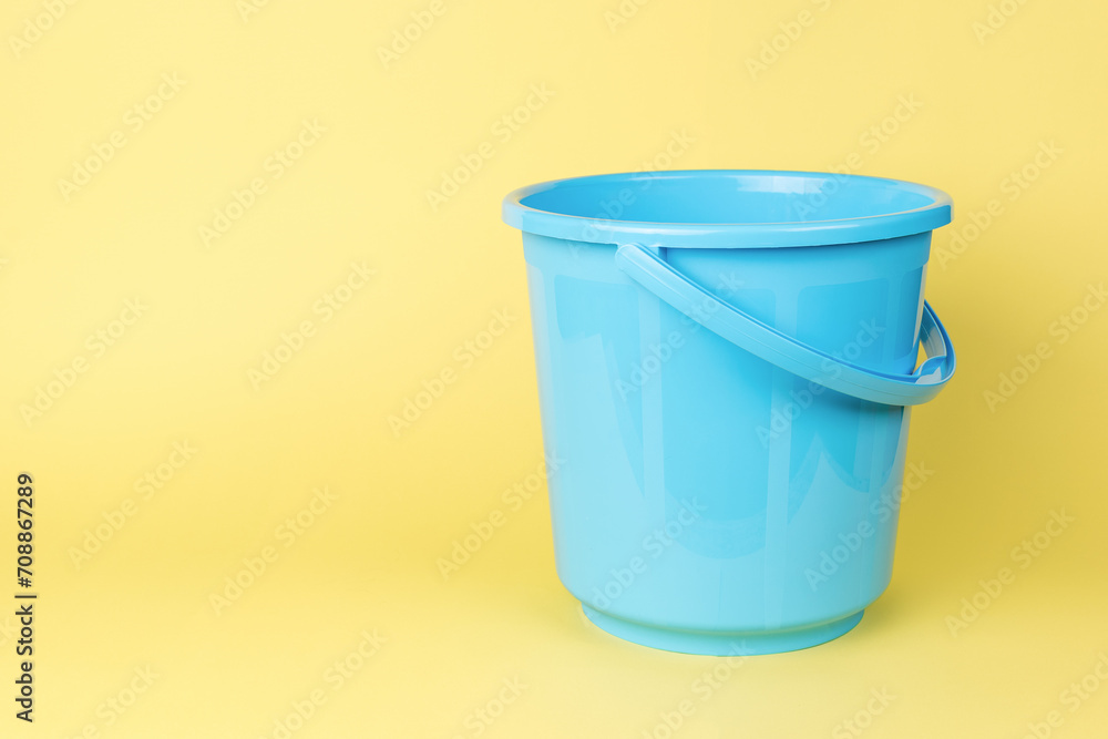 A blue plastic bucket on a yellow background. A blue plastic bucket on a yellow background.