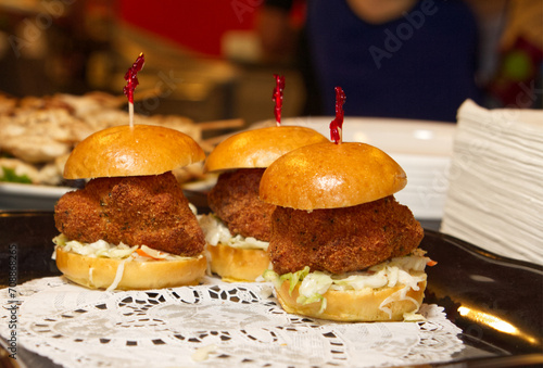 A trio of croquette sliders sit on a lace doily at an outdoor cafe.