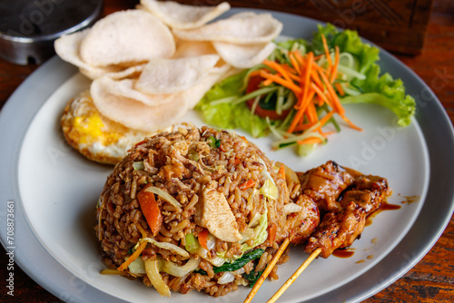 Traditional Indonesian food, fried rice with Fried Eggs, Satay, Crackers and Vegetables