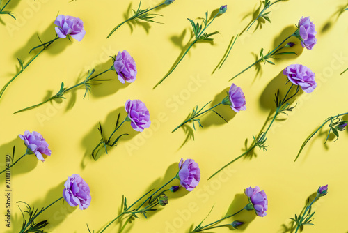 Lilac flowers with green stems creating a vibrant pattern on a luminous yellow backdrop