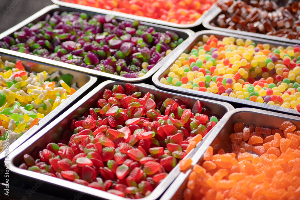 Multicolored candy gummies, red, yellow, green, blue displayed in containers