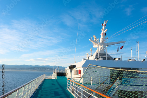 View from the upper open deck of a cruise ship on a bright sunny day against the background of a rocky shore