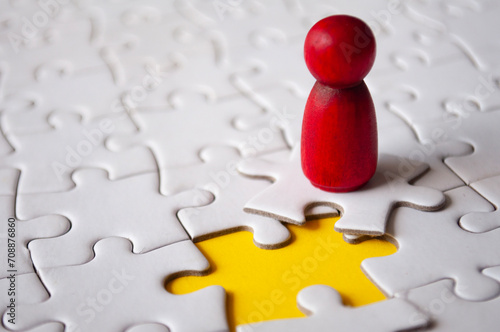 Canvas Print Red wooden doll on top of jigsaw with missing jigsaw puzzle