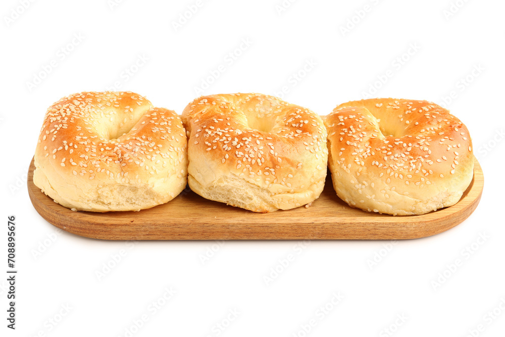 Wooden board of tasty bagels with sesame seeds on white background