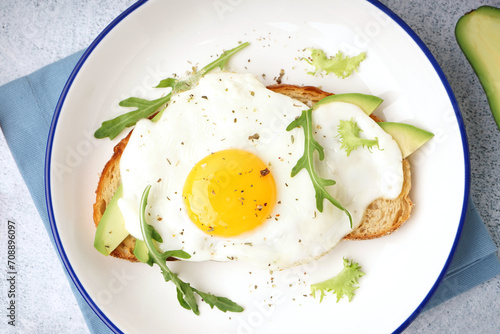 Delicious sandwich with fried egg  avocado and arugula on light background