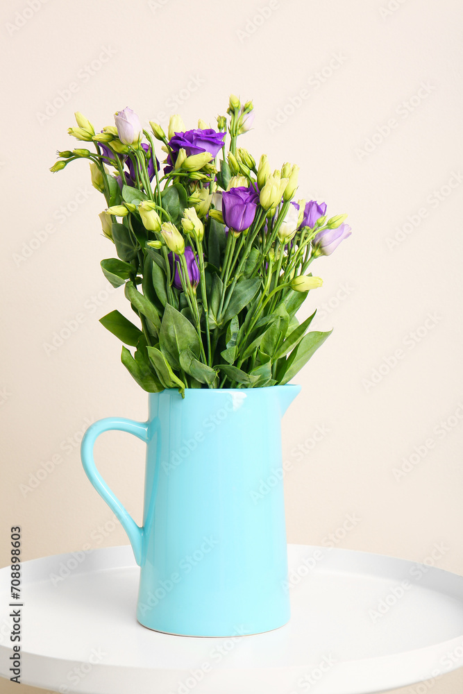 Jug with eustoma flowers on table near white wall Jug with eustoma flowers on table near white wall
