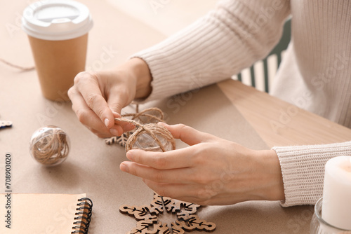 Woman decorating Christmas ball with jute rope on table photo