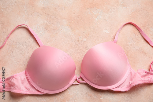 Pink female bra on color background, closeup