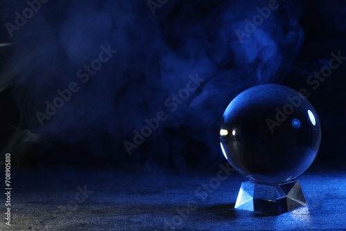 Magic crystal ball on table against dark background, space for text. Making predictions