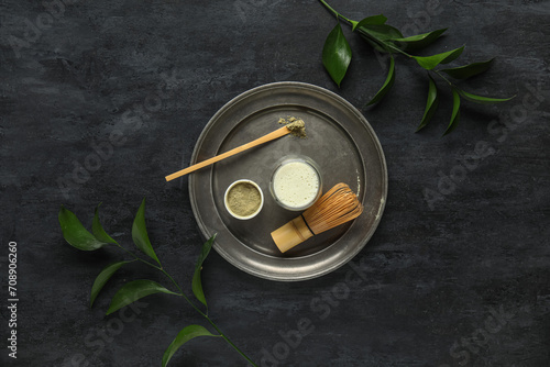 Composition with matcha tea, accessories and plant branches on dark background