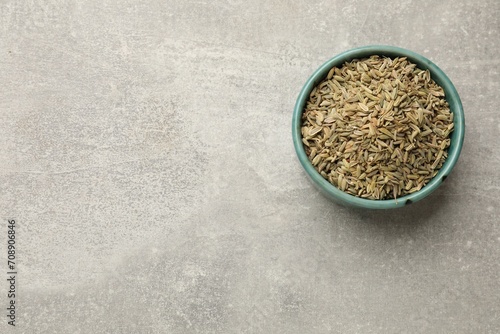 Fennel seeds in bowl on grey table, top view. Space for text