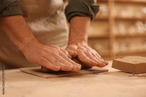 Man crafting with clay at table indoors, closeup