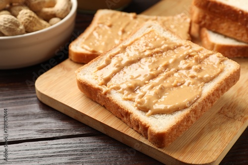 Delicious toasts with peanut butter on dark wooden table, closeup