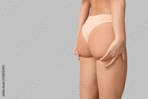 Young woman on panties on light background, back view. Plastic surgery concept