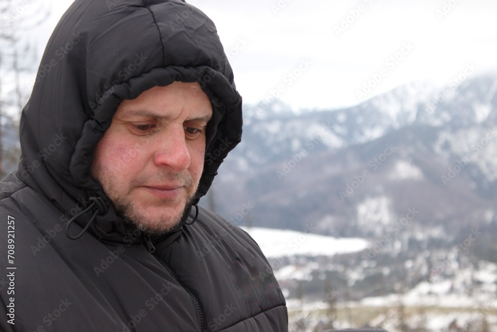 A middle-aged man drinks coffee against the background of snow-capped mountains