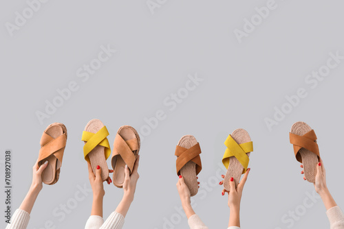 Female hands holding sandals on grey background photo