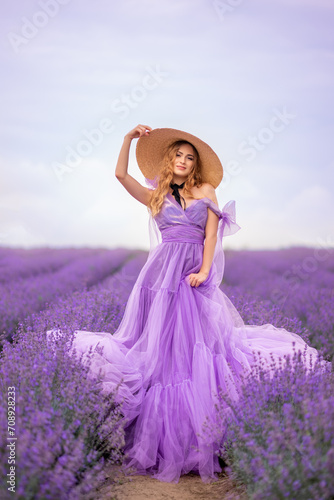 beautiful woman in a lush lilac dress in a field of lavender. She's wearing a big braided hat