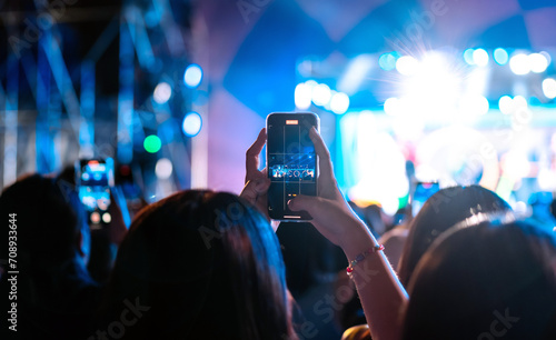 Girl holding smart phone and recording and photographing in music festival concert, party event background concept   © Keyframe's