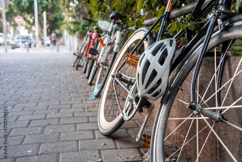 Bicycle with a helmet attached to the frame is parked on the side of the road. Safe driving. Eco transport. Urban transport (135)