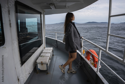 Istanbul. An Asian girl in a man's jacket is sailing on a ferry in Istanbul in cloudy weather, standing on the upper deck with a lifebuoy in the background photo