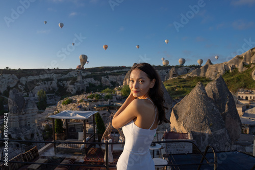 Fototapeta Naklejka Na Ścianę i Meble -  Cappadocia, Asian woman watches the flight of hot air balloons early in the morning in Cappadocia, tourism in Turkey