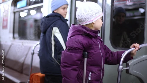 Boy and girl with roll-on bags in carriage of subway train, focus on girl. photo