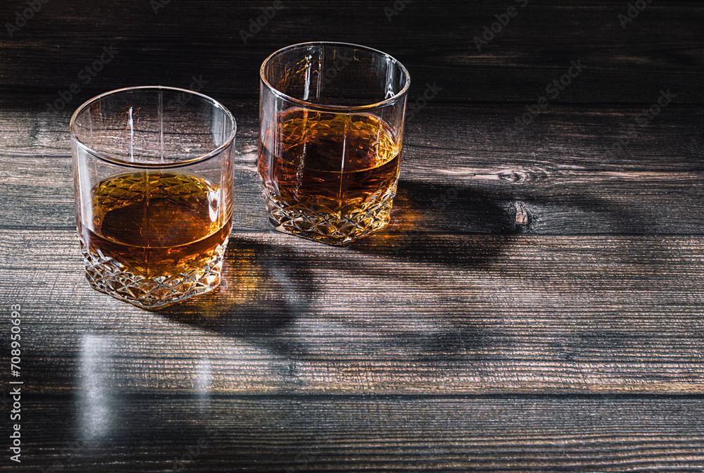 Two glasses with a drink on a wooden surface with a beautiful shadow Two glasses with a drink on a wooden surface with a beautiful shadow