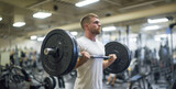 man lifting weights in gym, a man in a white shirt in a weight room lifts large barb